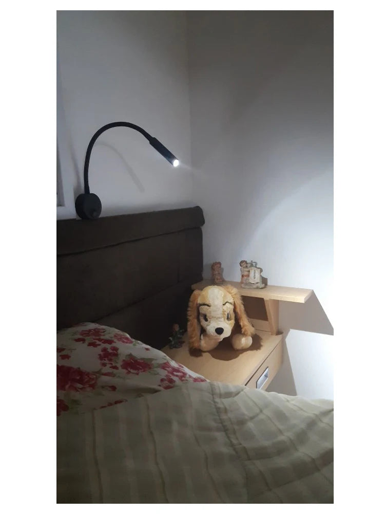 Modern LED wall reading light mounted beside a bed, providing focused lighting for reading.