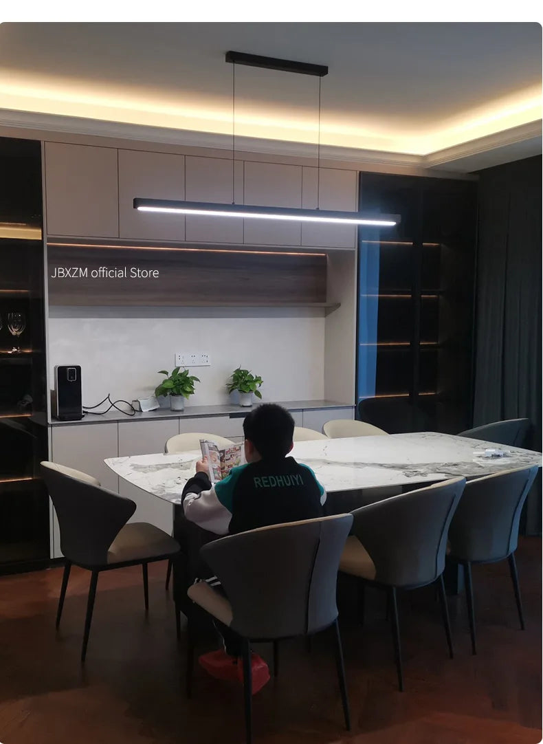 Modern linear LED pendant light suspended above a dining table in a contemporary dining room.