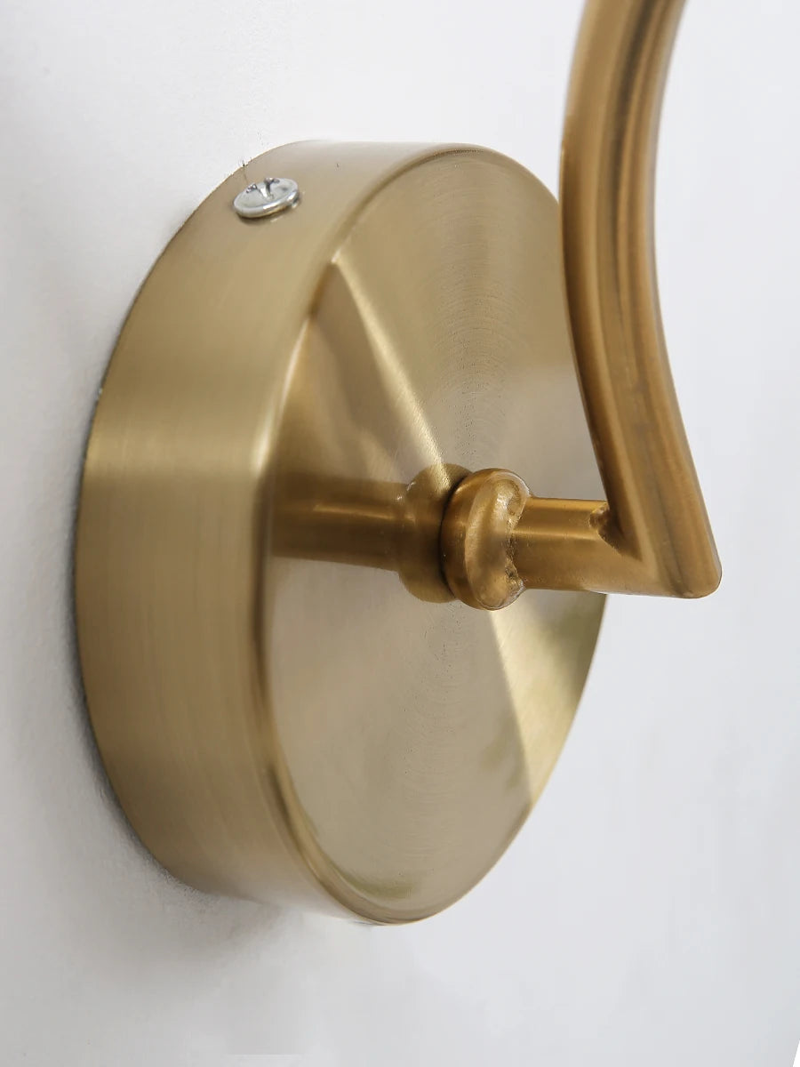 Modern Nordic glass LED wall sconce mounted beside a bed in a contemporary bedroom with warm ambient lighting.