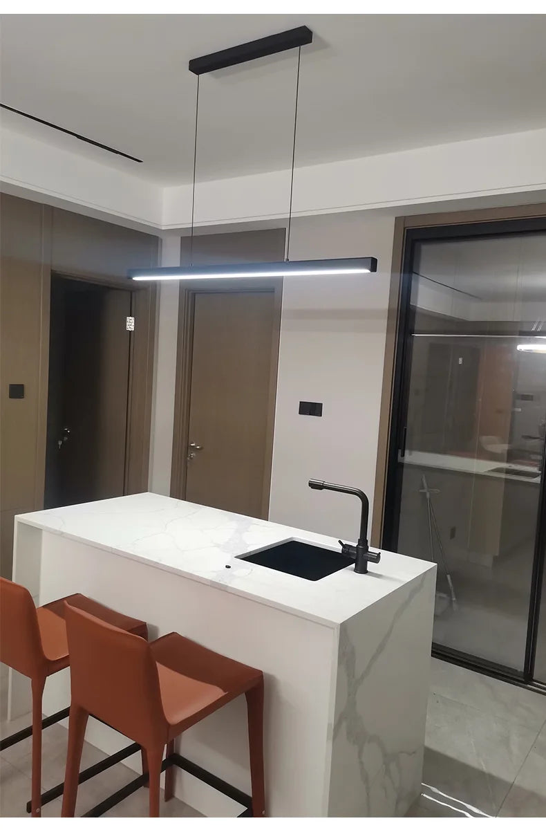 Modern linear LED pendant light suspended above a dining table in a contemporary dining room.