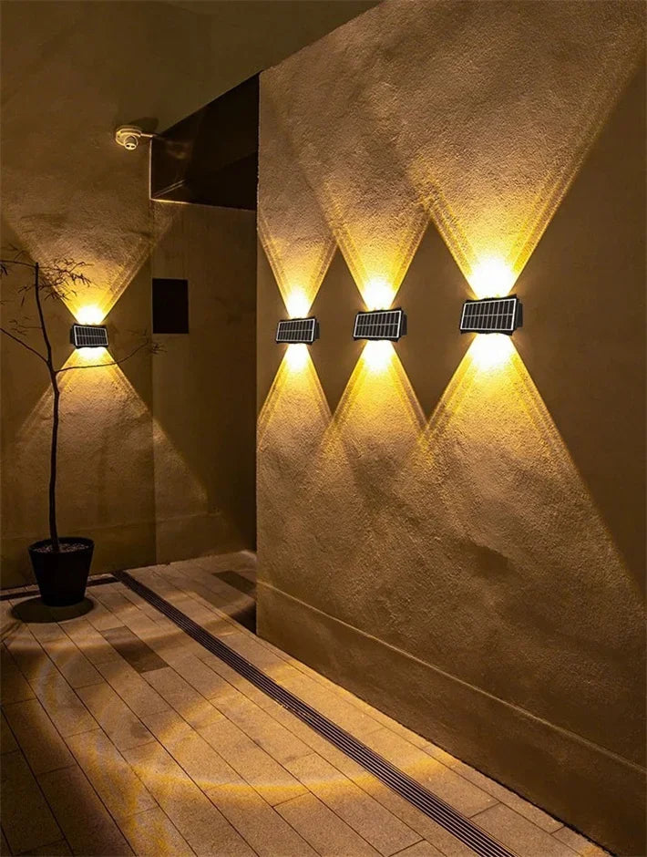 Modern waterproof solar LED wall light installed on an exterior wall illuminating a garden pathway.