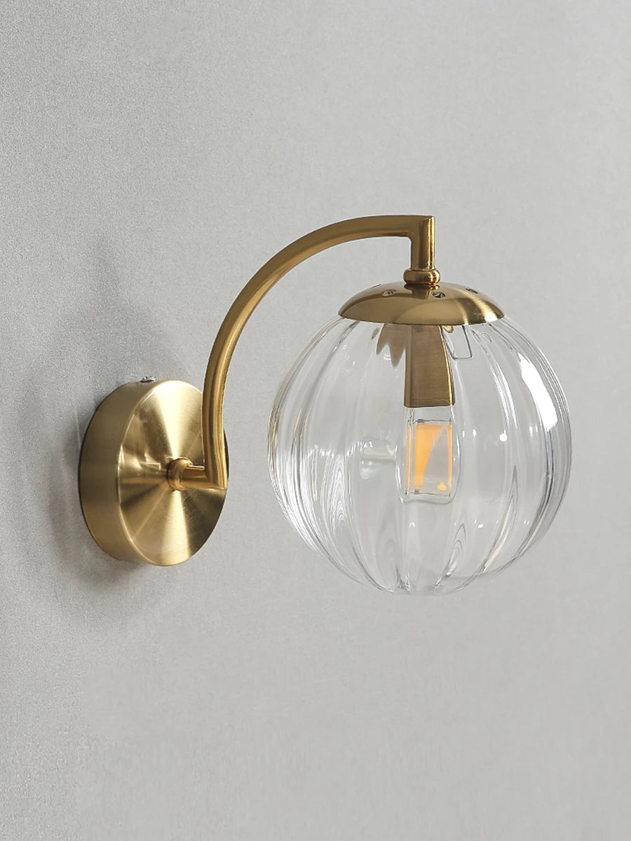 Modern Nordic glass LED wall sconce mounted beside a bed in a contemporary bedroom with warm ambient lighting.