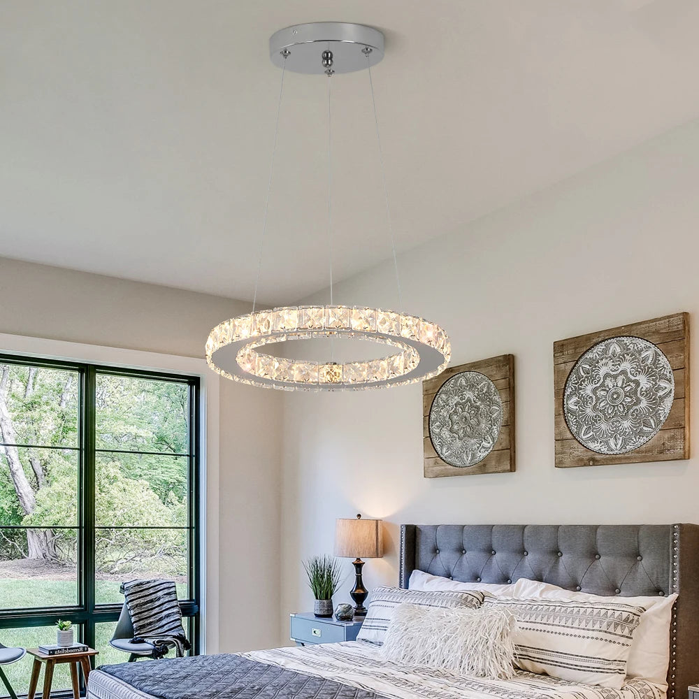 Luxury crystal ring LED chandelier suspended above a modern dining table in an elegant contemporary home.