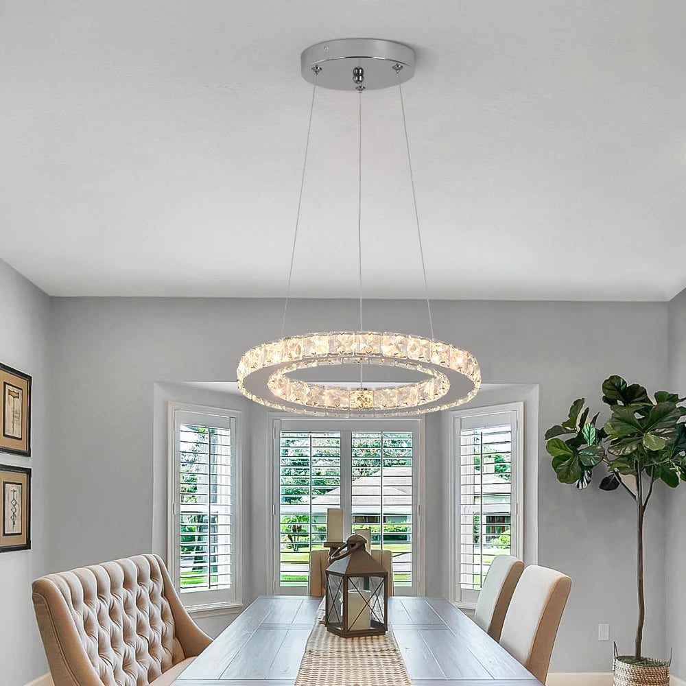 Luxury crystal ring LED chandelier suspended above a modern dining table in an elegant contemporary home.