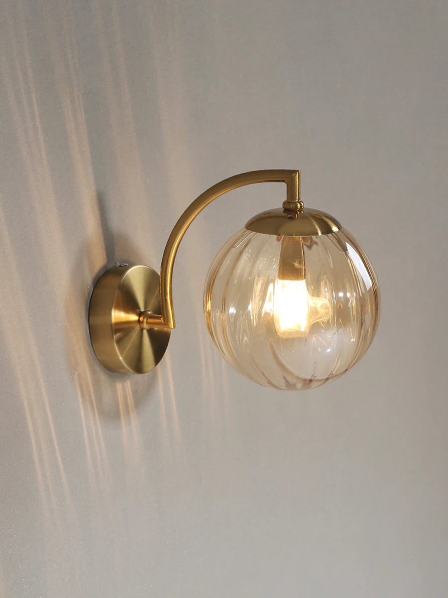 Modern Nordic glass LED wall sconce mounted beside a bed in a contemporary bedroom with warm ambient lighting.