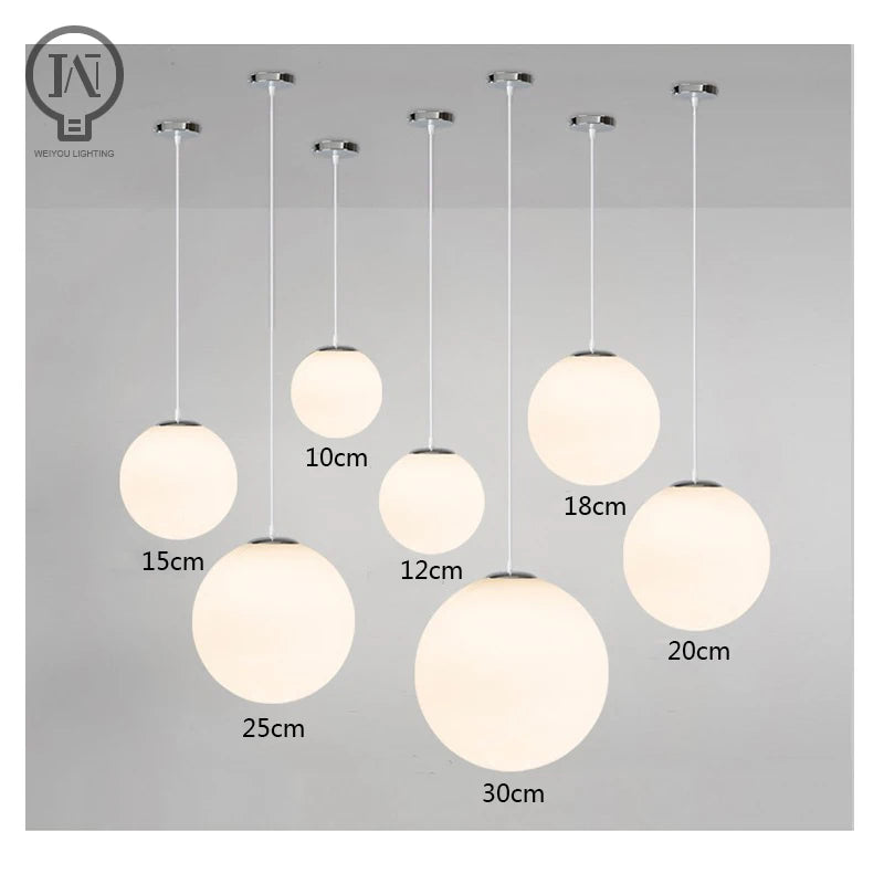 Modern glass globe pendant light with gold finish hanging above a contemporary dining table.