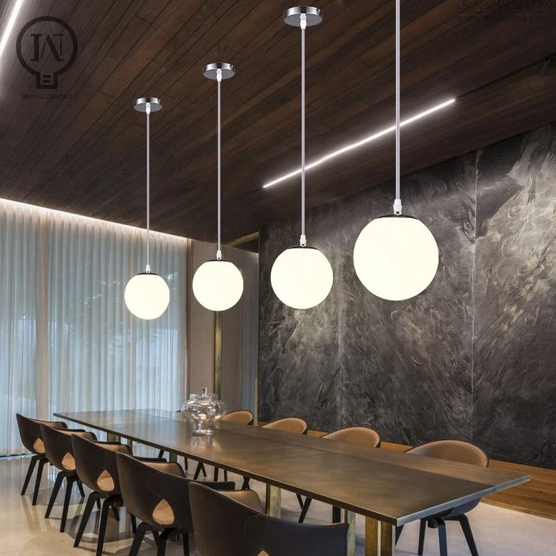 Modern glass globe pendant light with gold finish hanging above a contemporary dining table.