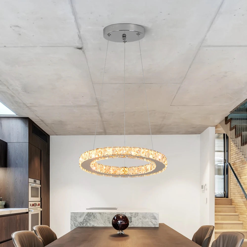 Luxury crystal ring LED chandelier suspended above a modern dining table in an elegant contemporary home.