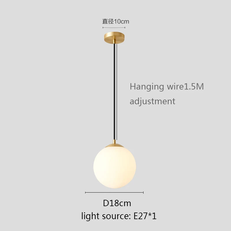 Modern glass globe pendant light with gold finish hanging above a contemporary dining table.
