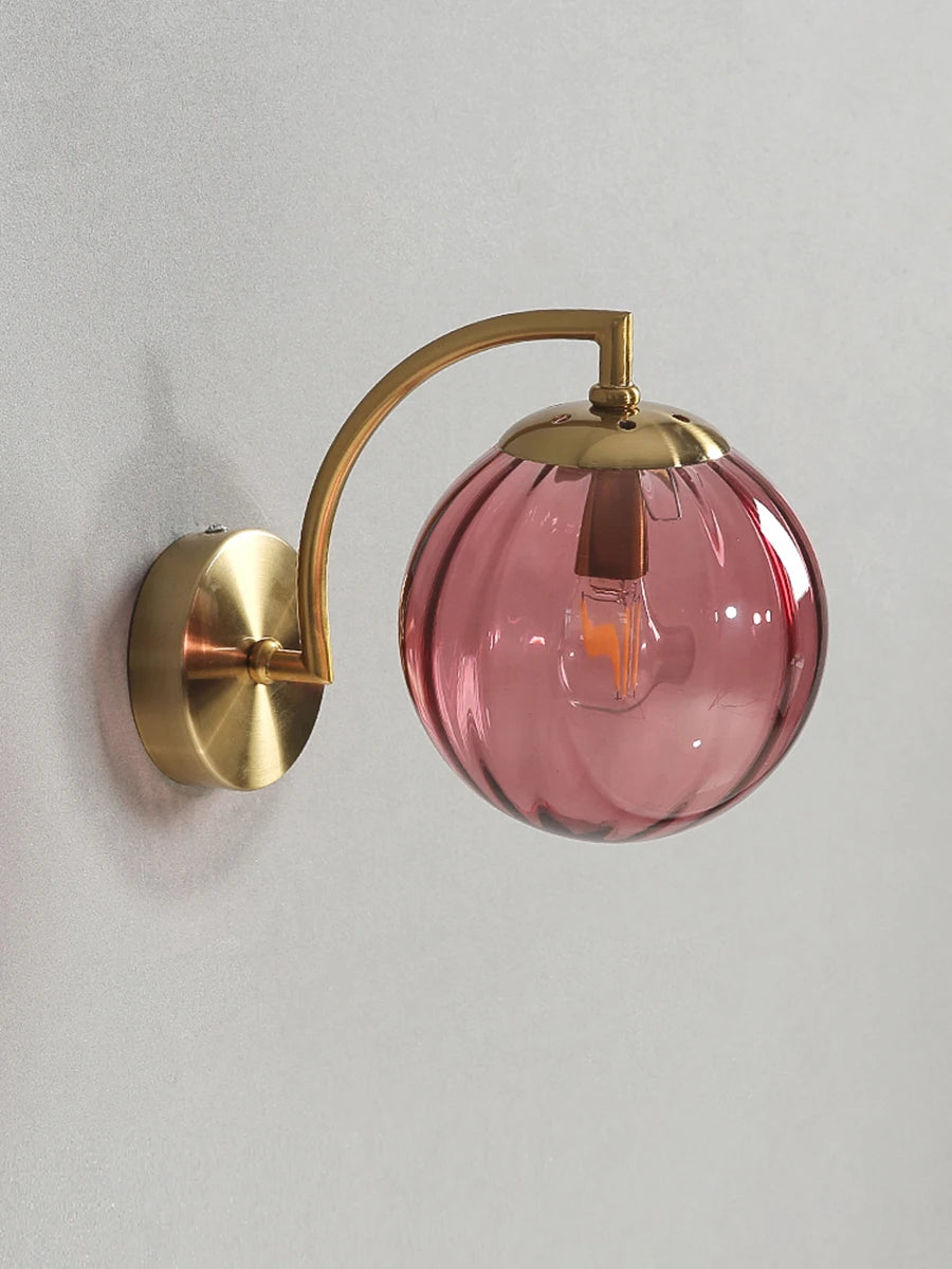 Modern Nordic glass LED wall sconce mounted beside a bed in a contemporary bedroom with warm ambient lighting.