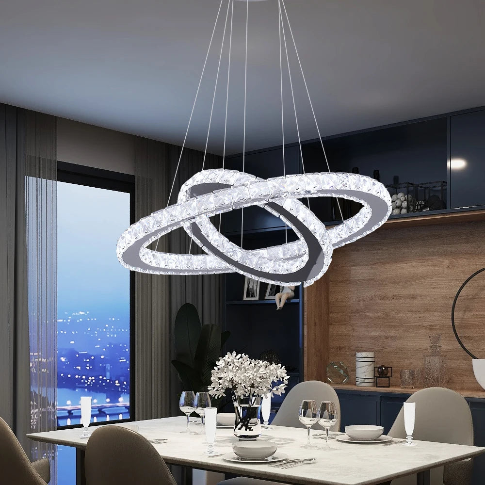 Luxury crystal ring LED chandelier suspended above a modern dining table in an elegant contemporary home.