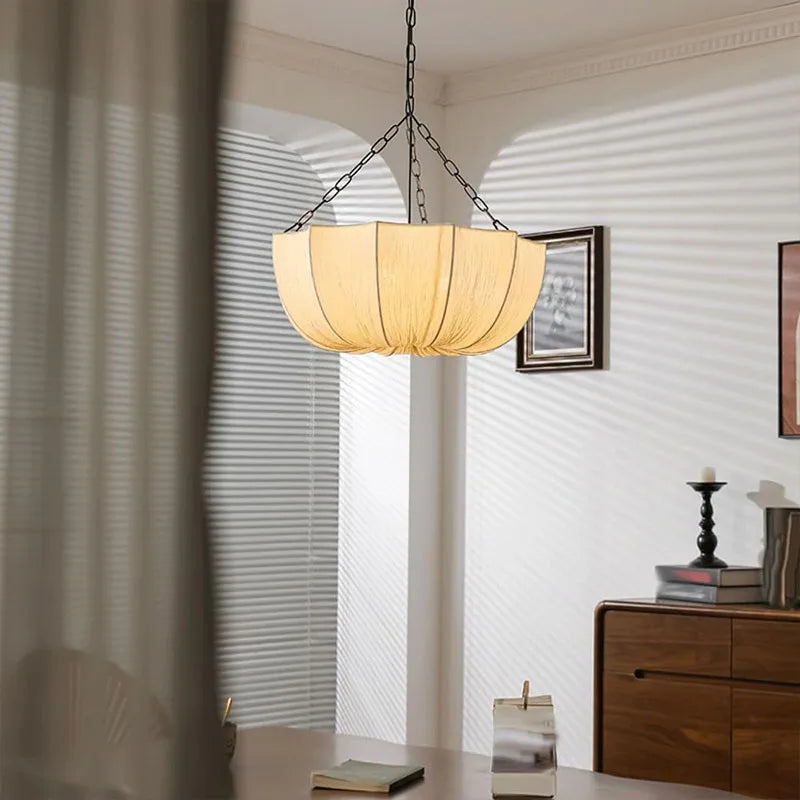 Japanese fabric pendant light with iron chain hanging above a modern dining table in a Japandi-style home.