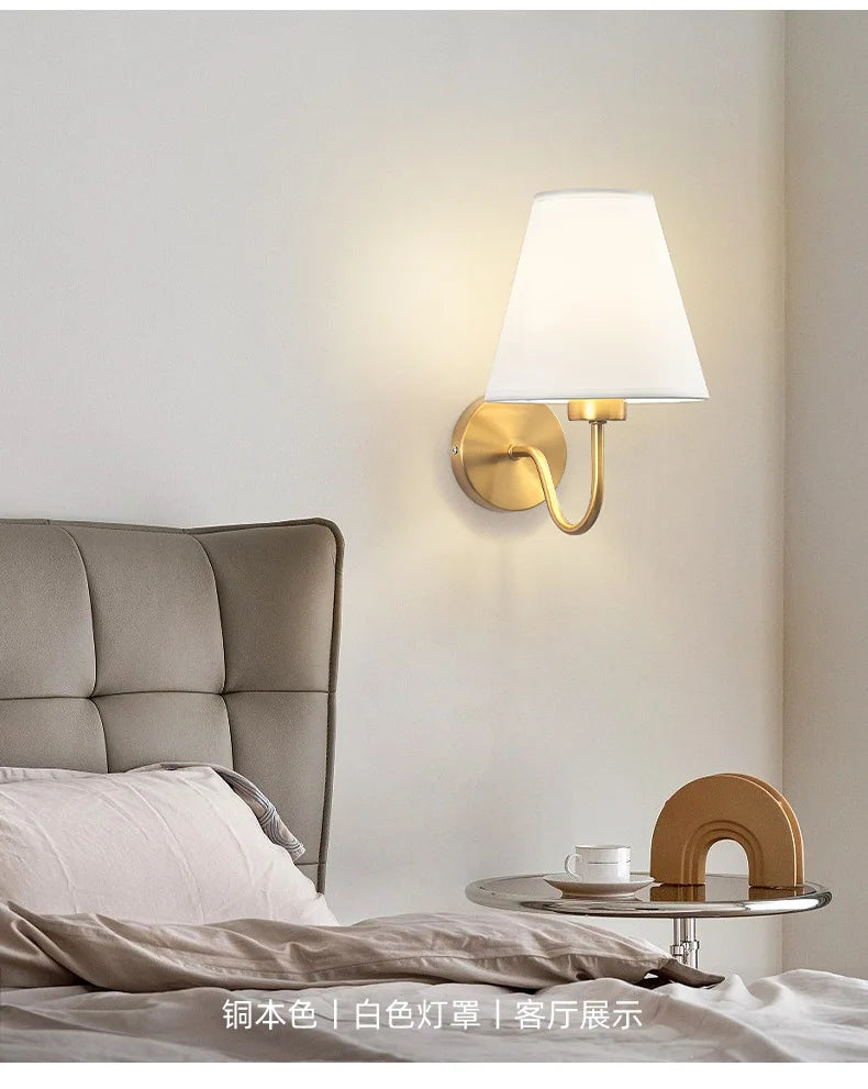 Modern fabric wall sconce installed beside a bed in a contemporary bedroom with warm ambient lighting.