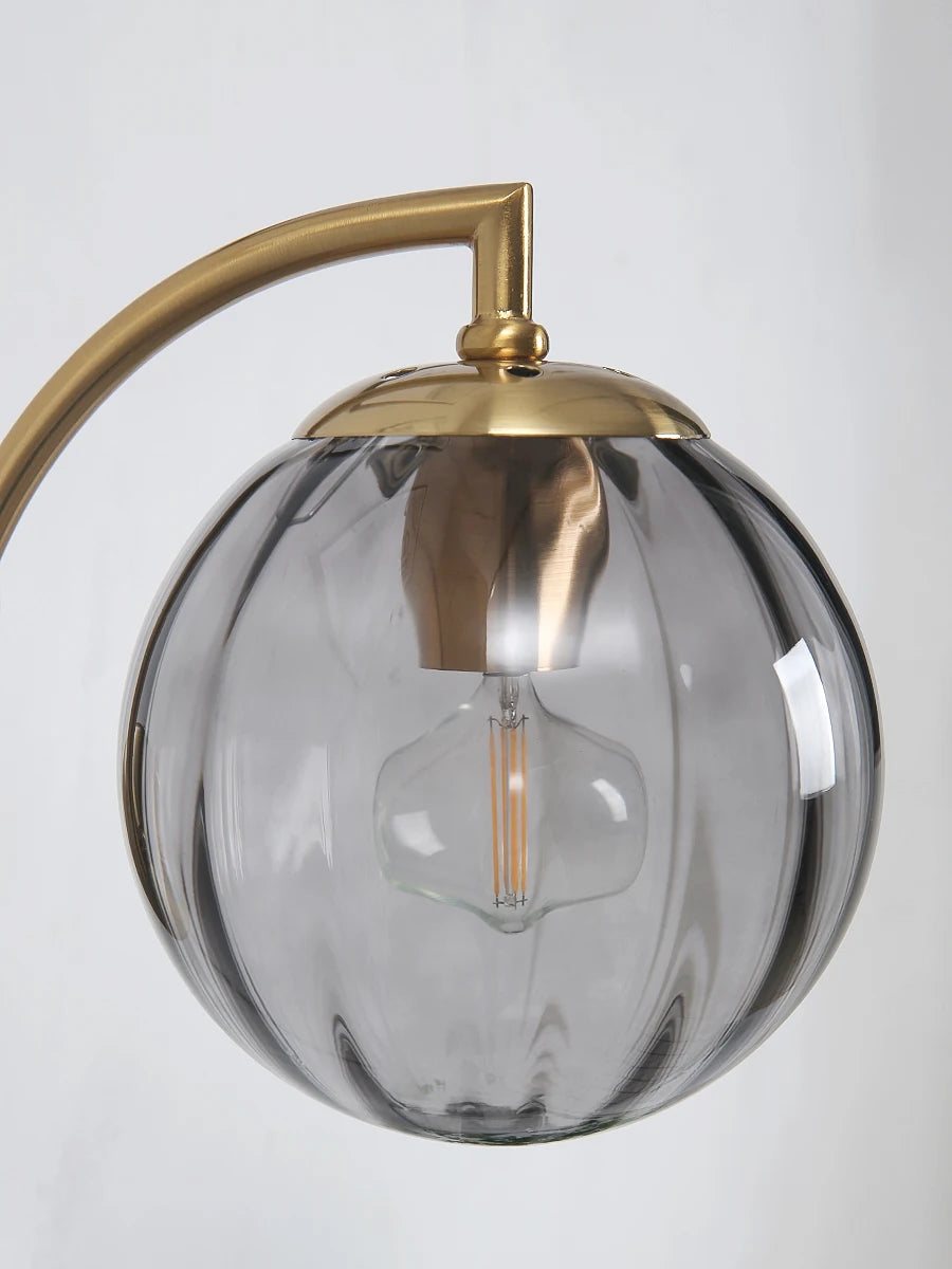 Modern Nordic glass LED wall sconce mounted beside a bed in a contemporary bedroom with warm ambient lighting.