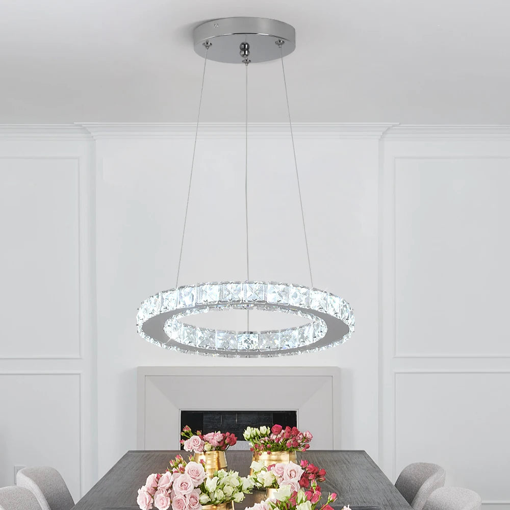 Luxury crystal ring LED chandelier suspended above a modern dining table in an elegant contemporary home.