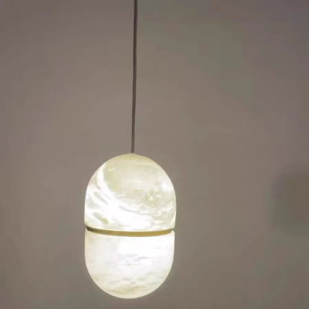 Luxury marble LED chandelier in a gold and black finish hanging above a modern dining table.