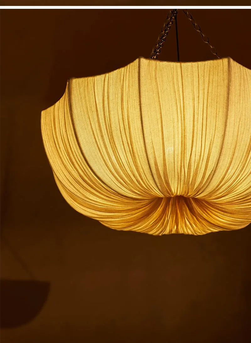 Japanese fabric pendant light with iron chain hanging above a modern dining table in a Japandi-style home.