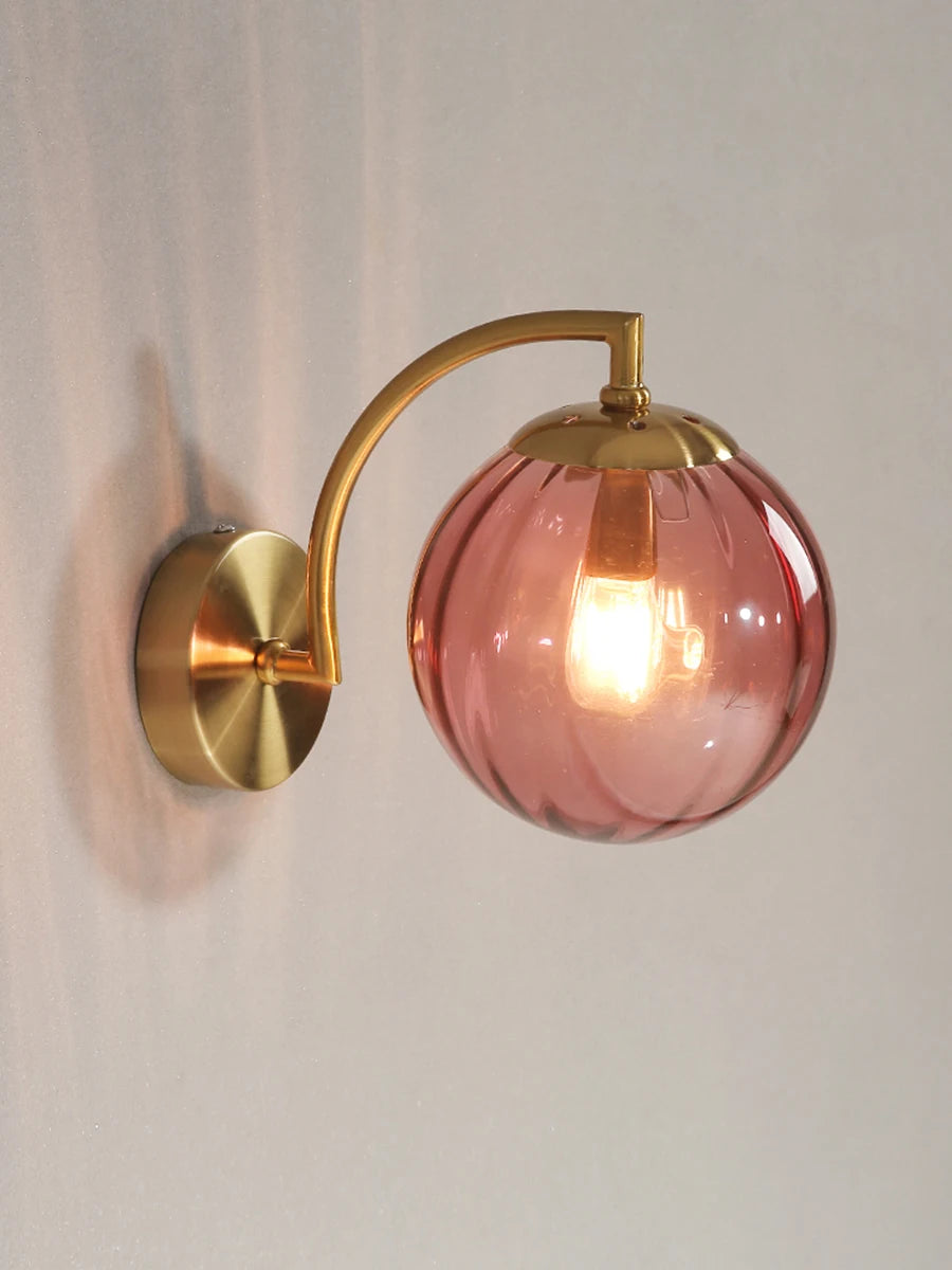 Modern Nordic glass LED wall sconce mounted beside a bed in a contemporary bedroom with warm ambient lighting.