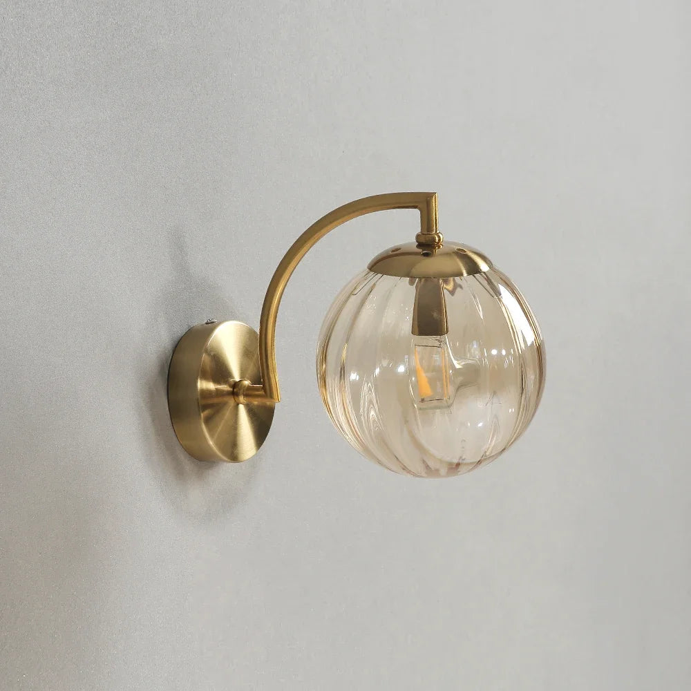 Modern Nordic glass LED wall sconce mounted beside a bed in a contemporary bedroom with warm ambient lighting.