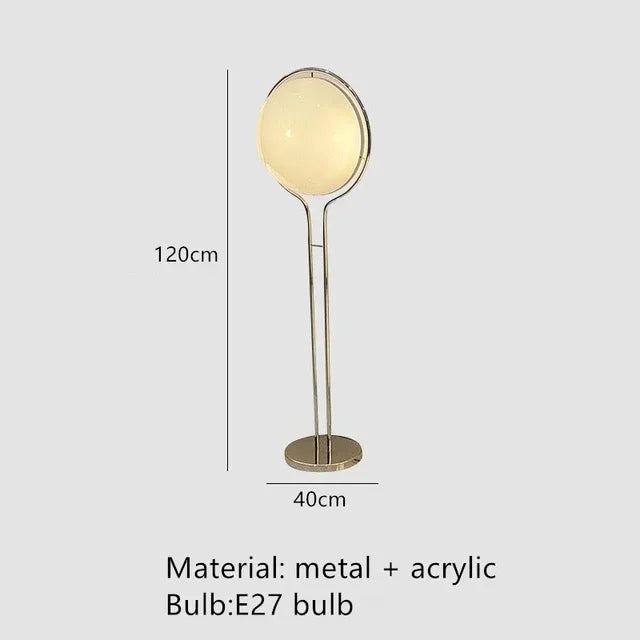 Luxury chrome globe floor lamp with a white acrylic globe beside a modern sofa in a contemporary living room.