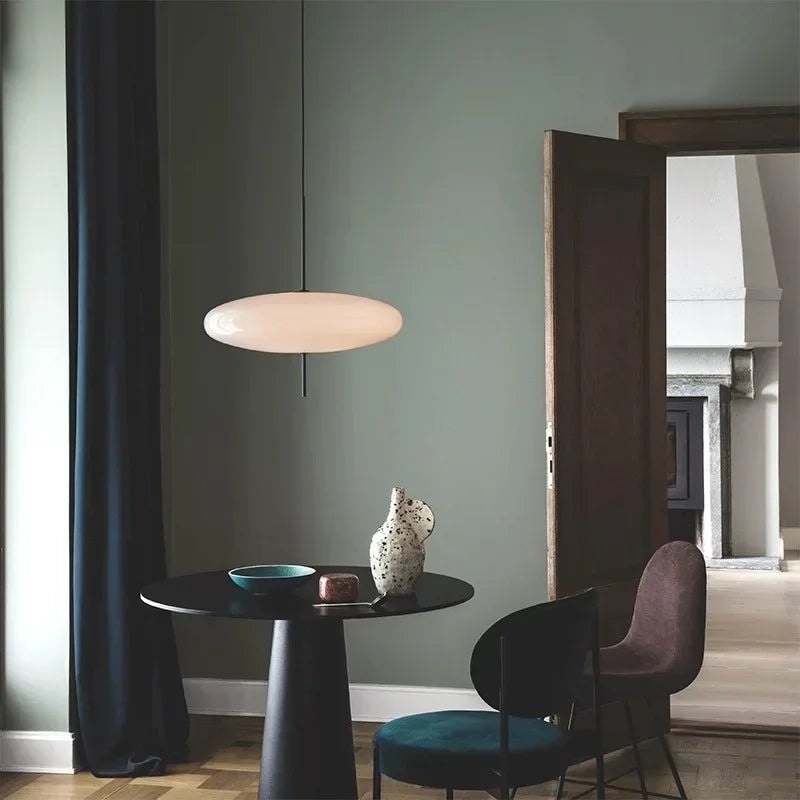 Nordic flying saucer LED pendant light hanging in a modern living room with minimalist décor.