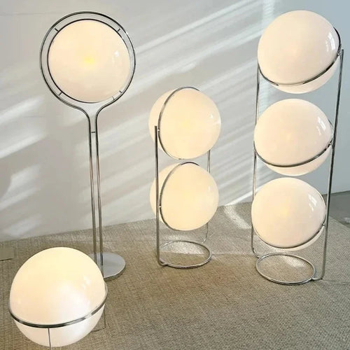 Luxury chrome globe floor lamp with a white acrylic globe beside a modern sofa in a contemporary living room.