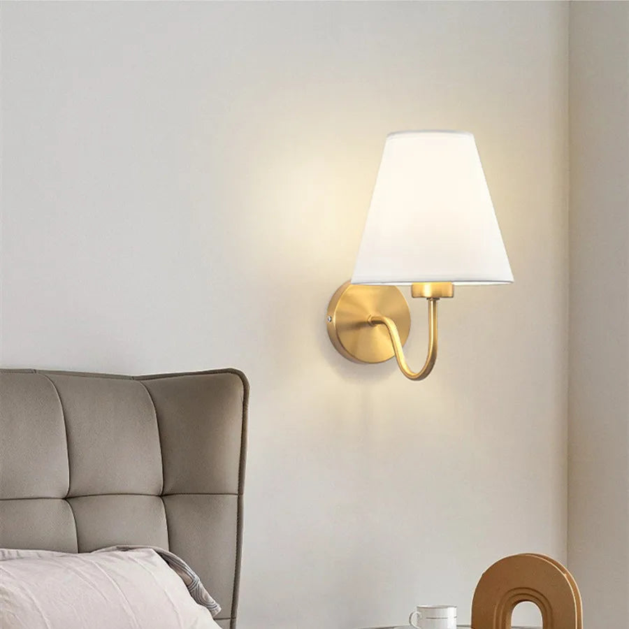 Modern fabric wall sconce installed beside a bed in a contemporary bedroom with warm ambient lighting.