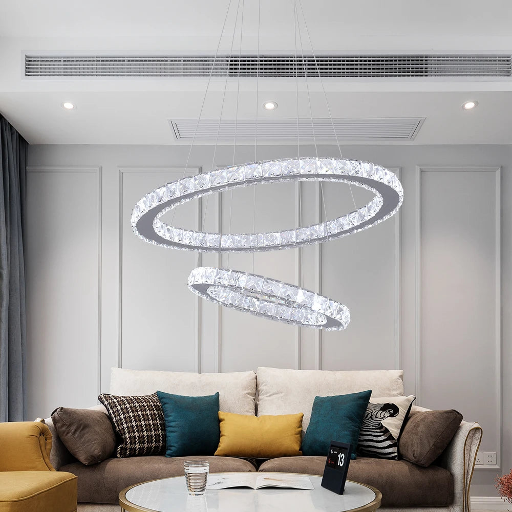 Luxury crystal ring LED chandelier suspended above a modern dining table in an elegant contemporary home.