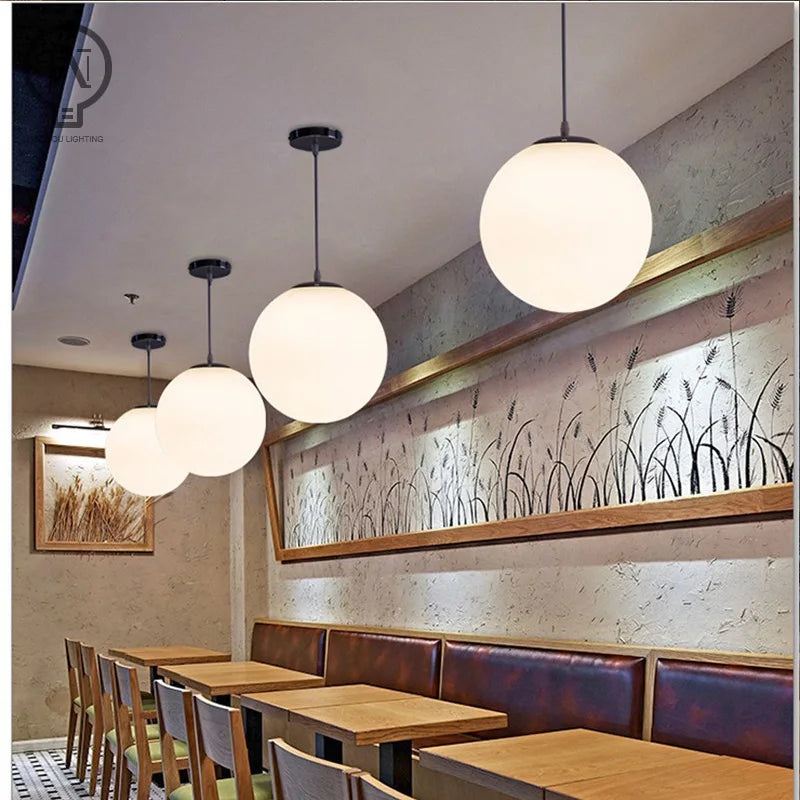 Modern glass globe pendant light with gold finish hanging above a contemporary dining table.