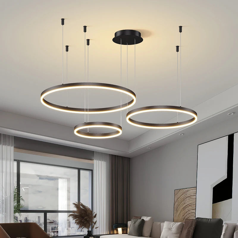 Modern LED circular ring chandelier installed above a dining table in a contemporary luxury home.