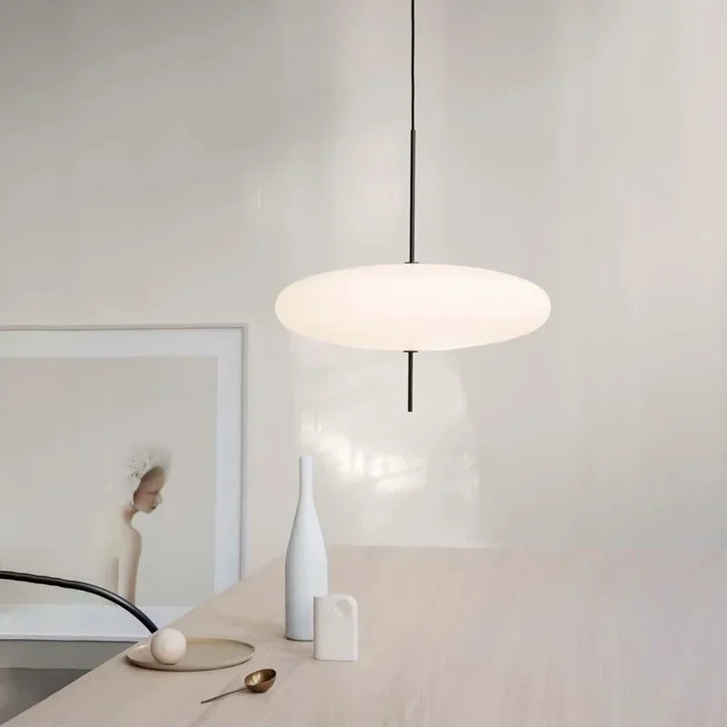 Nordic flying saucer LED pendant light hanging in a modern living room with minimalist décor.