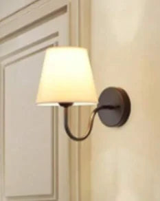 Modern fabric wall sconce installed beside a bed in a contemporary bedroom with warm ambient lighting.