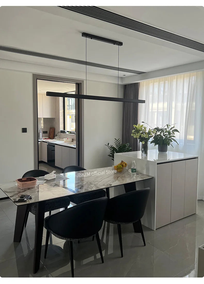 Modern linear LED pendant light suspended above a dining table in a contemporary dining room.