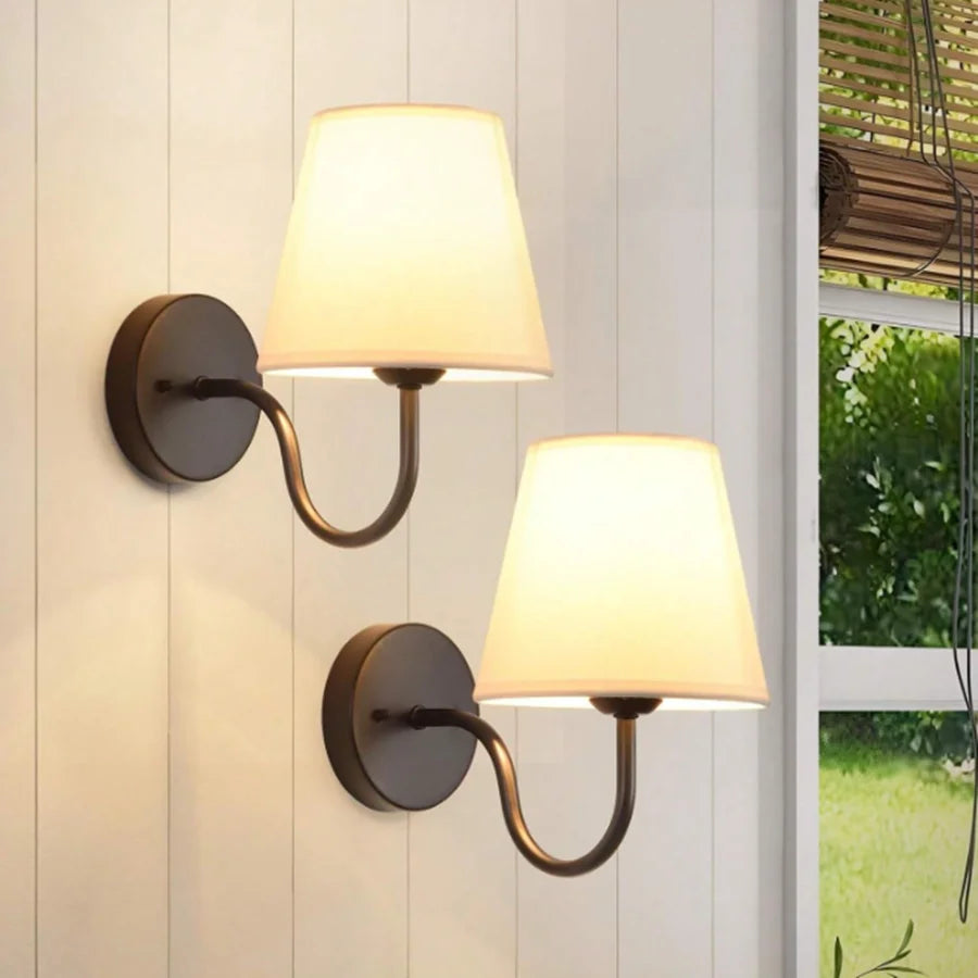Modern fabric wall sconce installed beside a bed in a contemporary bedroom with warm ambient lighting.