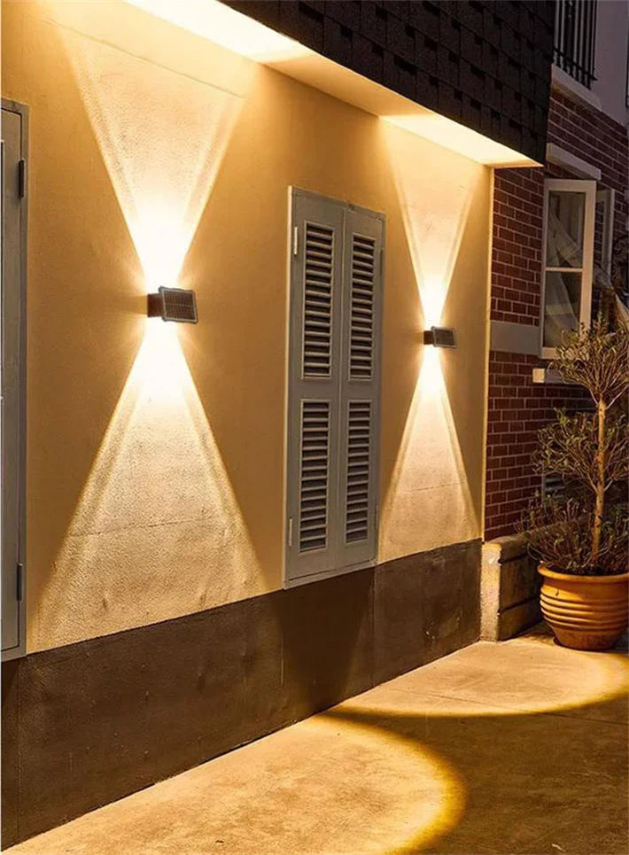 Modern waterproof solar LED wall light installed on an exterior wall illuminating a garden pathway.
