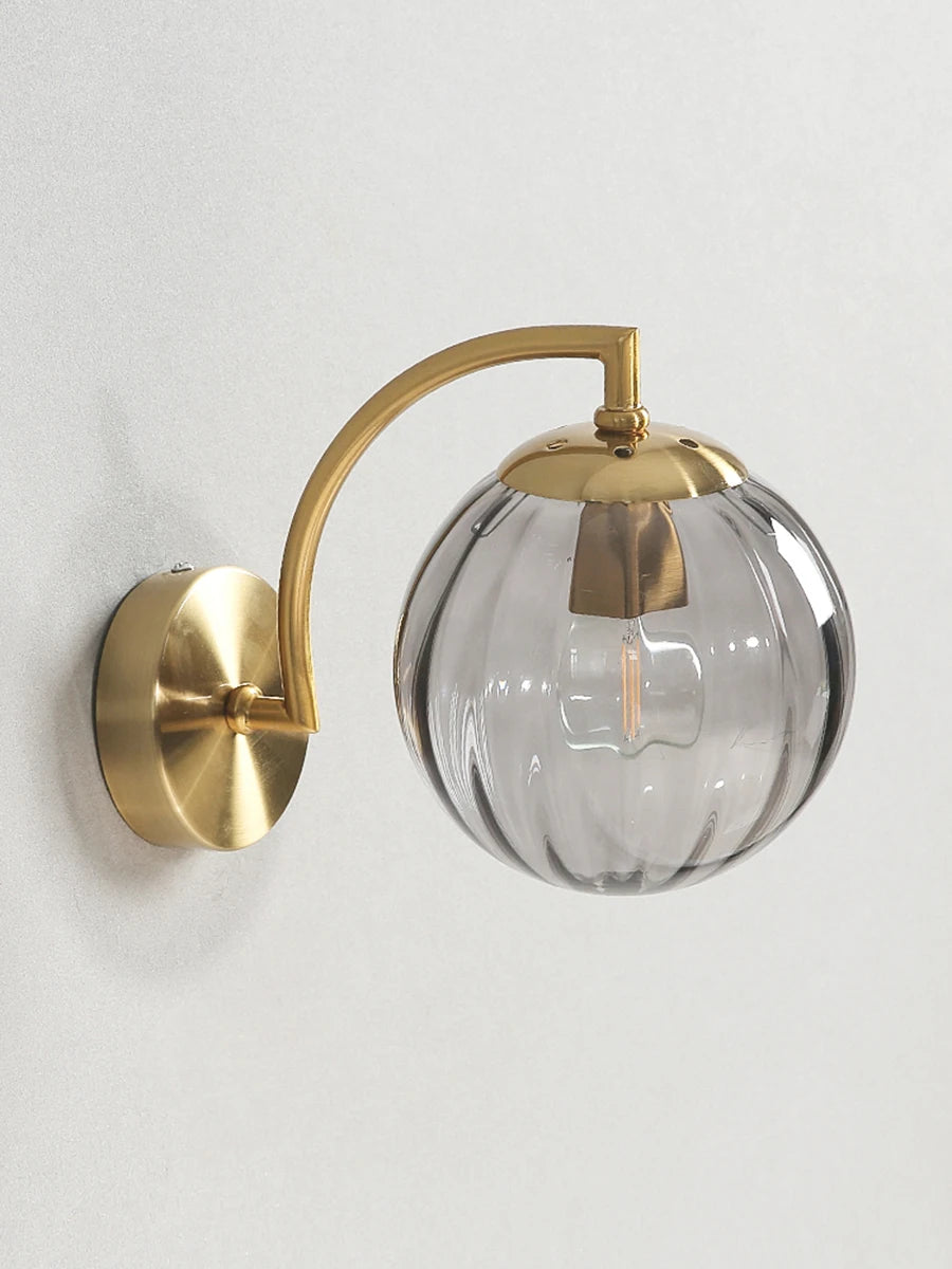 Modern Nordic glass LED wall sconce mounted beside a bed in a contemporary bedroom with warm ambient lighting.
