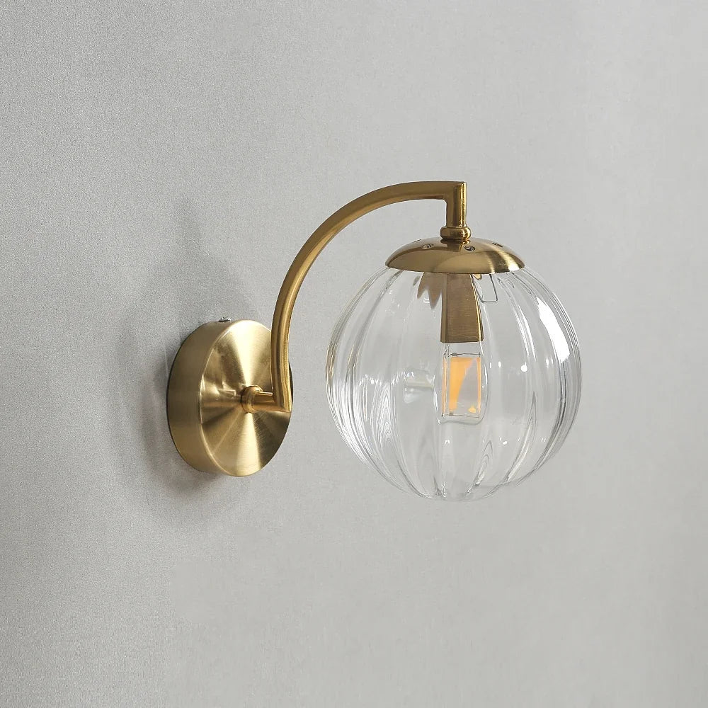 Modern Nordic glass LED wall sconce mounted beside a bed in a contemporary bedroom with warm ambient lighting.