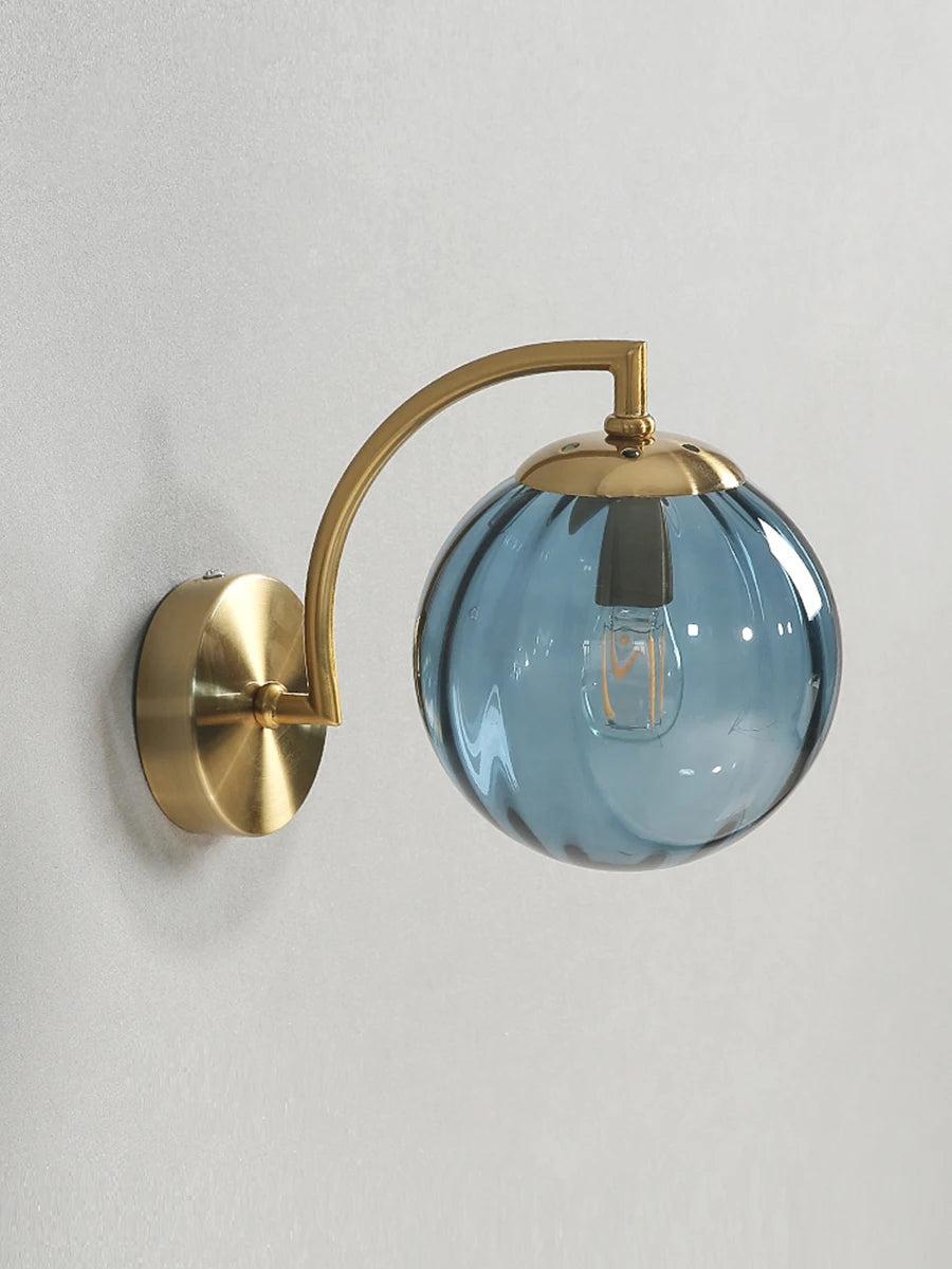 Modern Nordic glass LED wall sconce mounted beside a bed in a contemporary bedroom with warm ambient lighting.