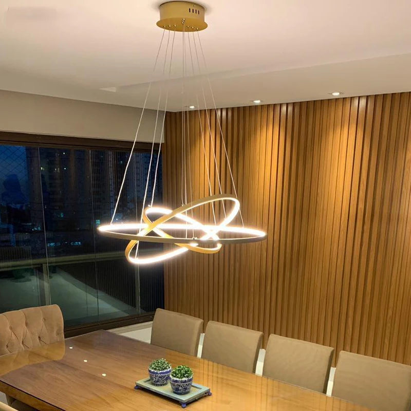 Modern LED ring chandelier suspended above a dining table in a luxury contemporary home.