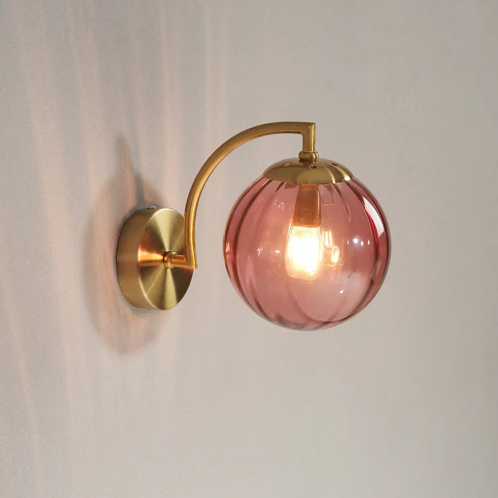 Modern Nordic glass LED wall sconce mounted beside a bed in a contemporary bedroom with warm ambient lighting.