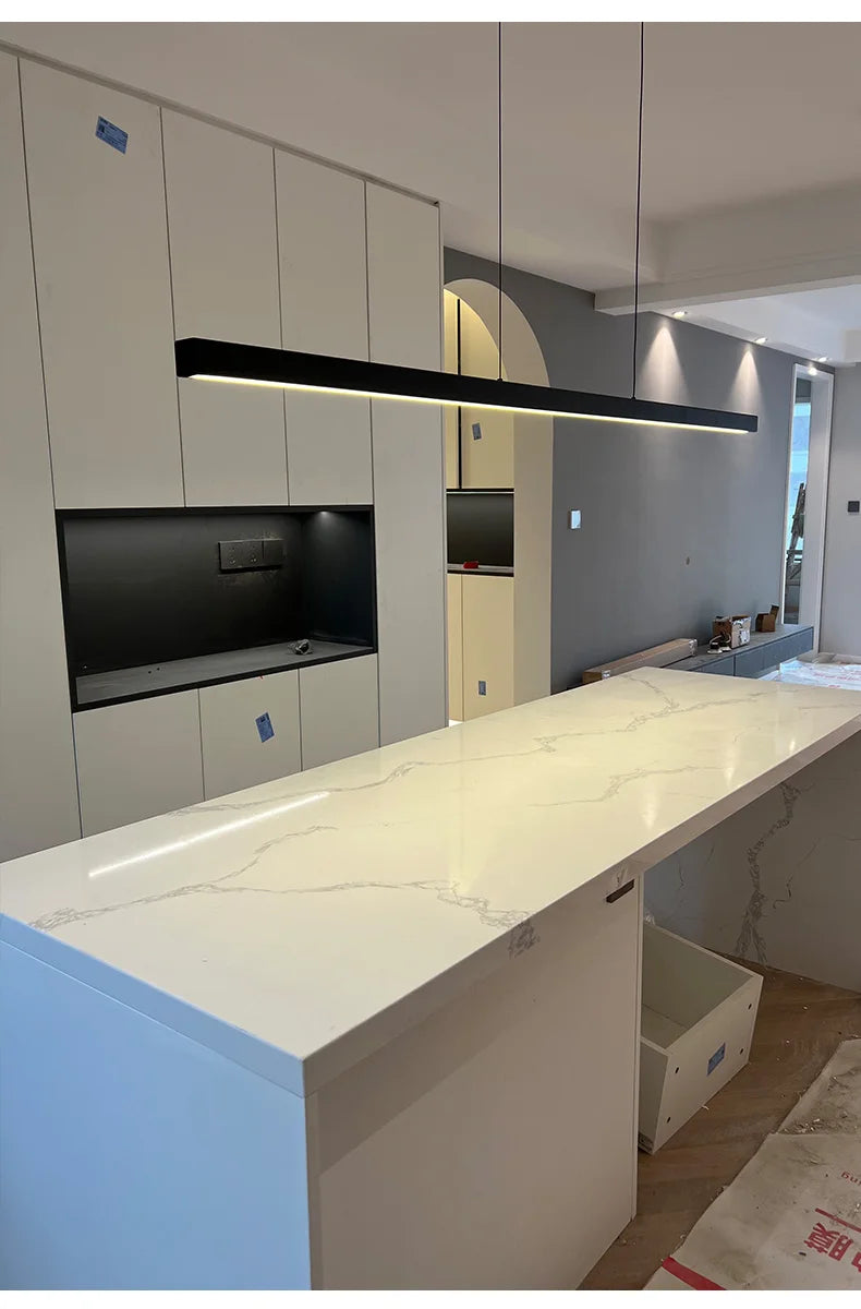 Modern Linear LED Pendant Light hanging above a sleek white kitchen island with a contemporary design.