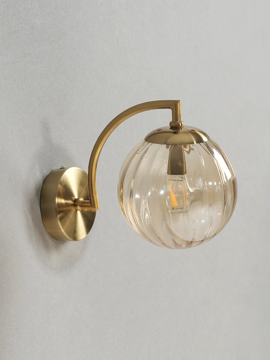 Modern Nordic glass LED wall sconce mounted beside a bed in a contemporary bedroom with warm ambient lighting.