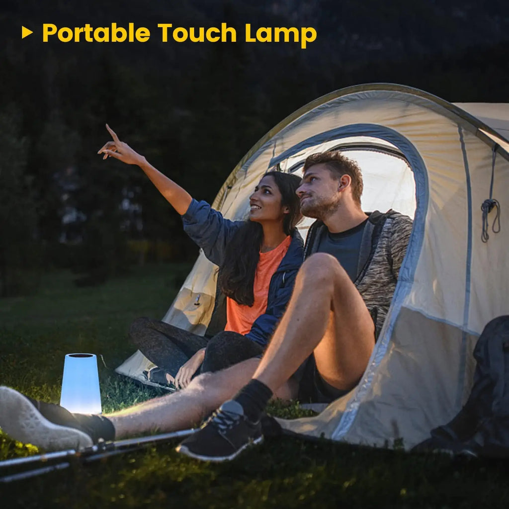 Couple enjoying a Rechargeable RGB Bedside Table Lamp outside their tent during camping.