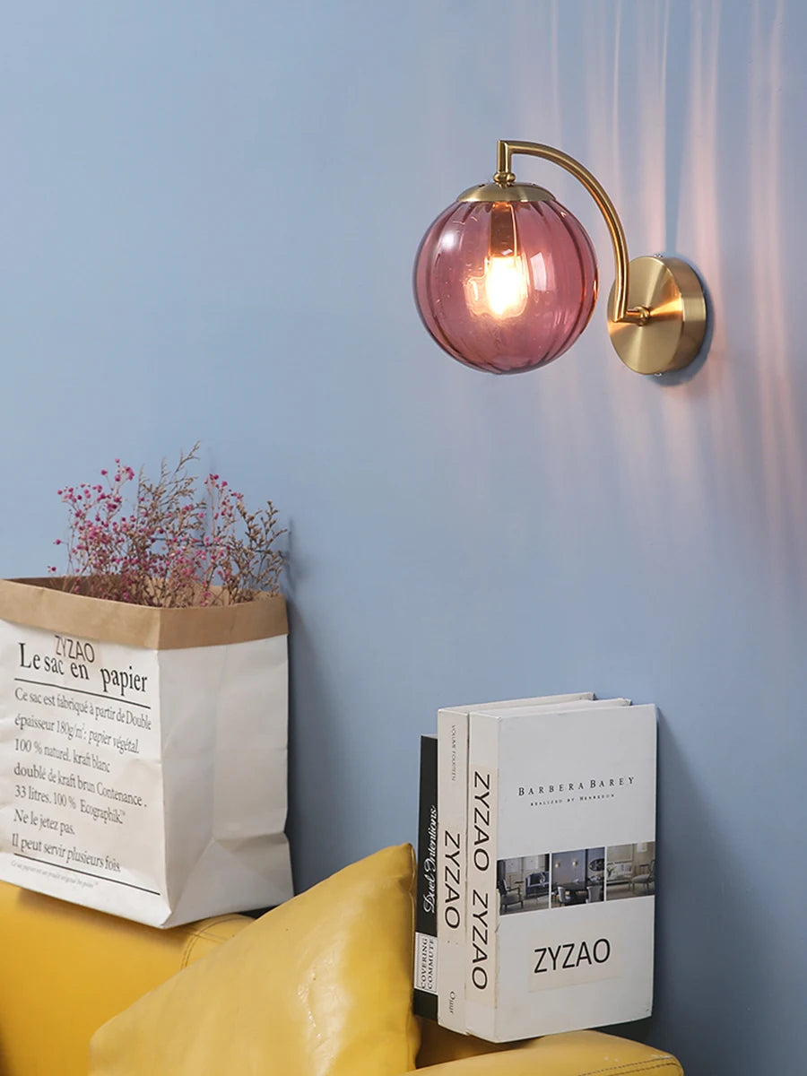 Modern Nordic glass LED wall sconce mounted beside a bed in a contemporary bedroom with warm ambient lighting.