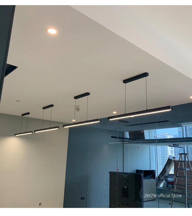 Modern linear LED pendant light suspended above a dining table in a contemporary dining room.