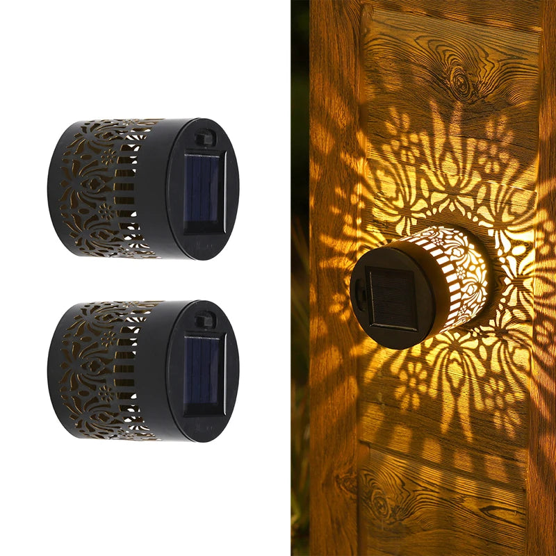 Modern waterproof solar projection LED wall light casting a decorative light pattern on an outdoor garden wall.