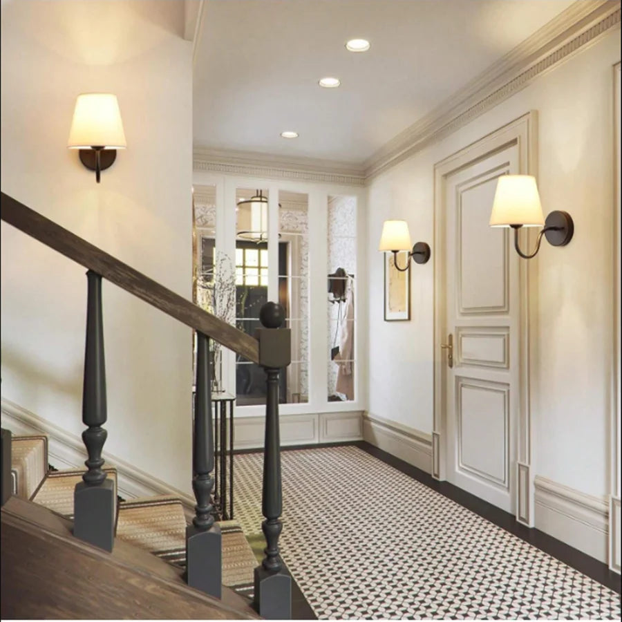 Modern fabric wall sconce installed beside a bed in a contemporary bedroom with warm ambient lighting.