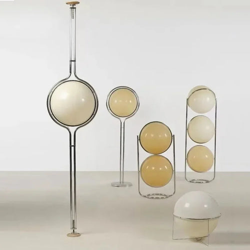 Luxury chrome globe floor lamp with a white acrylic globe beside a modern sofa in a contemporary living room.