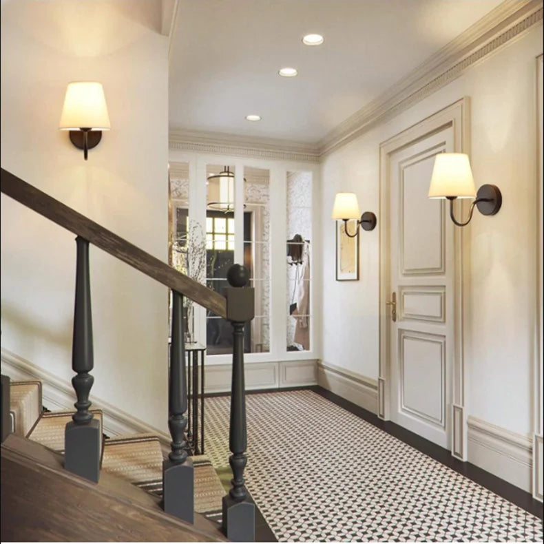 Modern fabric wall sconce installed beside a bed in a contemporary bedroom with warm ambient lighting.