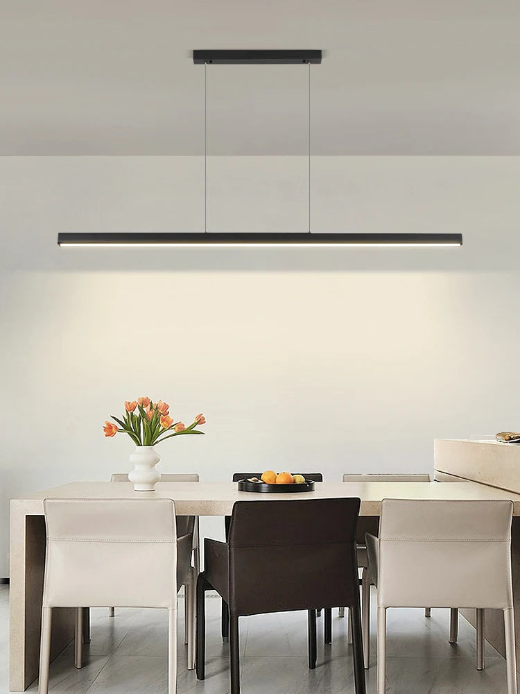 Modern linear LED pendant light suspended above a dining table in a contemporary dining room.